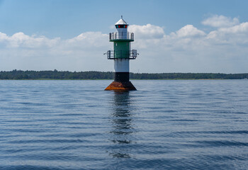 Navigation green buoy or beacon on in the calm blue sea water