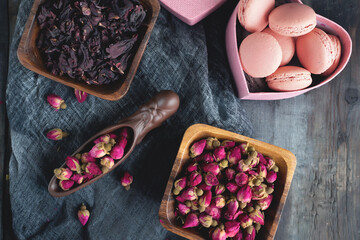 there is a teaspoon of rosebud tea on the wooden table. Tea time, cozy atmosphere. Kitchen still life in Chinese style with pink floral tea on a background of contrasting morning light. Top view
