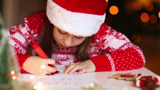 child draws santa claus on christmas letter. girl paints with marker