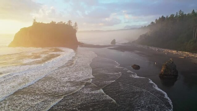 Flying over Ruby beach at sunset, Oregon, United States. Magnificent black beach in fog, cliffs and waves of the Pacific Ocean. Aerial drone shot