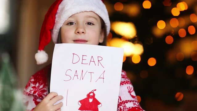 child holds letter for santa claus in his hands with inscription dear santa and christmas drawing