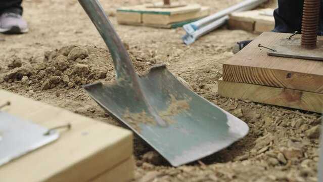 Close up, scooping dirt with shovel at a construction site. Slow motion