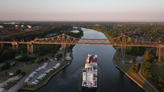 Aerial time lapse from fluctuation on the famous railway Rendsburg High Bridge over Kiel Canal with aerial transfer bridge, train  and container ship.
