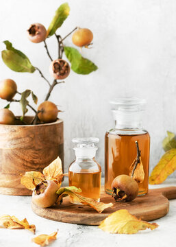 Homemade medlar fruit syrup or juice in pharmacy glasses on wooden cutting board. Alternative medicine concept. Copy space. (Mespilus germanica)