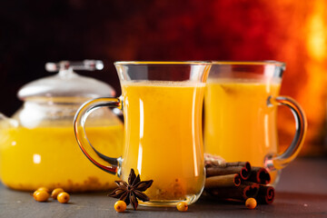 Two glass cups of hot sea buckthorn tea with orange juice, cinnamon and anise.