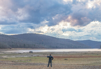 Obraz premium Man taking a selfie with his phone on a waters age lake mountain landscape