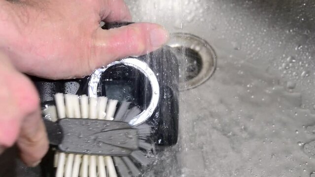 Washing dirty dslr camera in water. Crazy photographer poorly cleans the camera sensor with water. Crazy camera cleaning