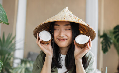 Fashion. Asian woman in summer clothes with coconut in tropical nature background. Beautiful...