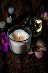 burning aroma candle on a dark wooden background, components of spa treatments, vertical