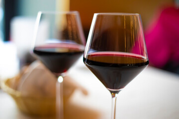 Two glasses of red wine standing on a table in a restaurant
