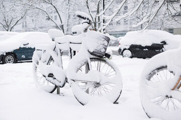 Winter in a city, street covered by snow, beautiful  snowy winter scene on town with bicycles and cars covered by snow - obrazy, fototapety, plakaty