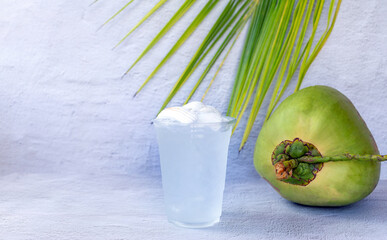 Ice coconut water drink in a plastic glass and coconut on white background