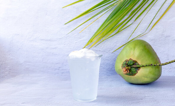 Ice coconut water drink in a plastic glass and coconut on white background