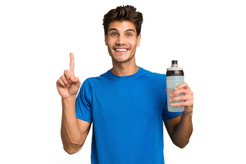 Young sport caucasian man holding a bottle of water isolated showing number one with finger.