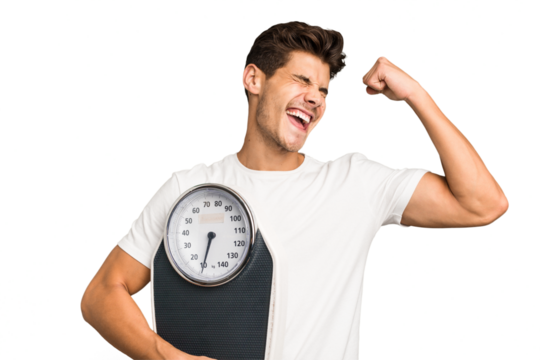 Young caucasian man holding a scale isolated raising fist after a victory, winner concept. - Powered by Adobe