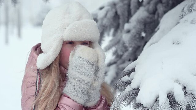 portrait cute joyful girl child 10 years old with ruddy red cheeks in winter clothes outdoors in the snow smiling looking at the camera. High quality 