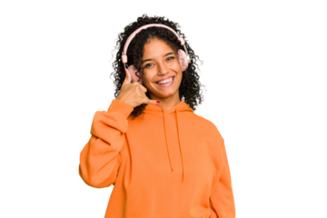 Young Brazilian woman listening to music with headphones isolated showing a mobile phone call gesture with fingers.