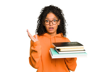 Young student woman holding a pile of books isolated surprised and shocked.
