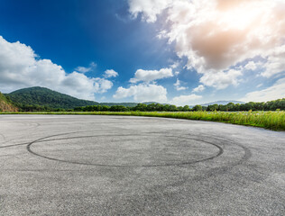 Empty asphalt road and green mountain with sky clouds background