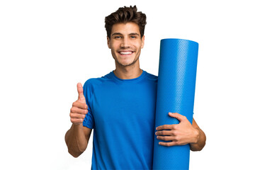 Young caucasian sport man holding a mat isolated smiling and raising thumb up
