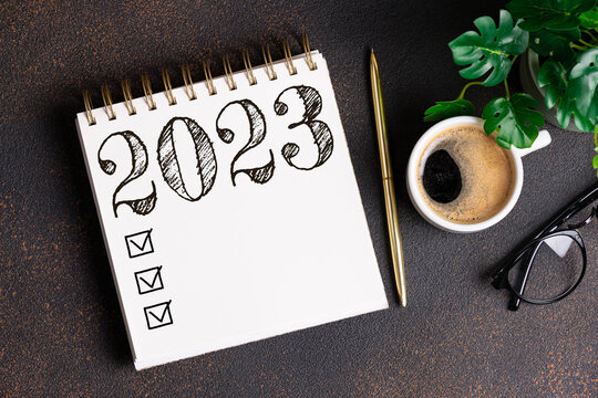 New year resolutions 2023 on desk. 2023 resolutions list with notebook, coffee cup on table. Goals, resolutions, plan, action, checklist concept. New Year 2023 background. Copy space