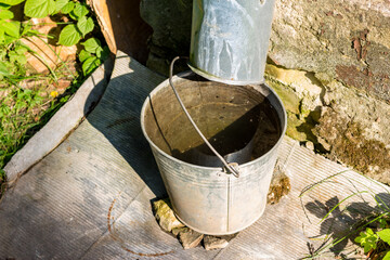 A metal bucket installed under a storm pipe on the corner of a residential building