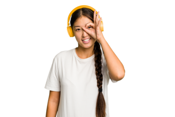 Young asian woman listening to music with headphones isolated excited keeping ok gesture on eye.