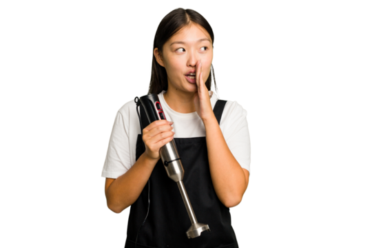 Young asian cook woman holding a blender isolated is saying a secret hot braking news and looking aside