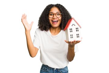 Young african american woman moving to a new home while picking up a box full of things isolated receiving a pleasant surprise, excited and raising hands.