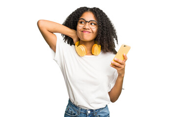 Young african american woman listening to music with yellow headphones isolated touching back of head, thinking and making a choice.
