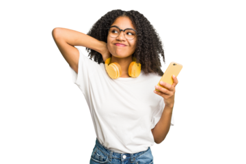 Young african american woman listening to music with yellow headphones isolated touching back of head, thinking and making a choice.