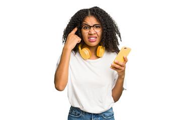 Young african american woman listening to music with yellow headphones isolated showing a disappointment gesture with forefinger.