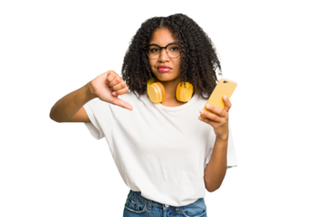 Young african american woman listening to music with yellow headphones isolated showing a dislike gesture, thumbs down. Disagreement concept.