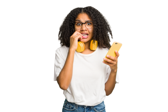 Young african american woman listening to music with yellow headphones isolated biting fingernails, nervous and very anxious.