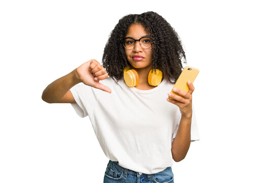Young african american woman listening to music with yellow headphones isolated showing a dislike gesture, thumbs down. Disagreement concept.