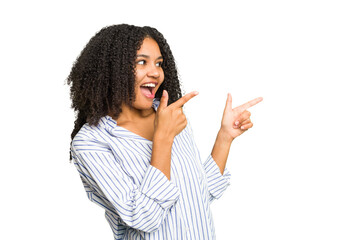 Young african american woman isolated points with thumb finger away, laughing and carefree.