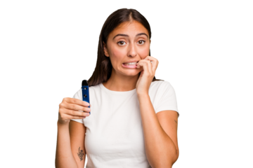 Young caucasian woman holding a electronic cigarette biting fingernails, nervous and very anxious.