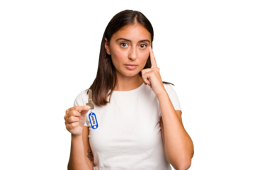 Young caucasian woman holding a home keys isolated pointing temple with finger, thinking, focused on a task.