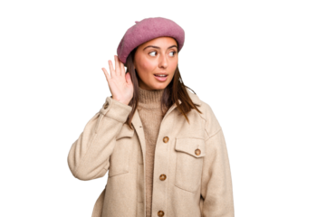 Young caucasian woman wearing winter jacket isolated trying to listening a gossip.