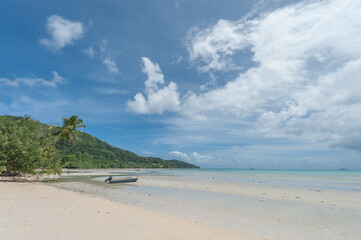 Beach in Seychelles with Ocean Water and Blue Sky with Clouds. Landscape. Low Tide Water. Boat in Background.