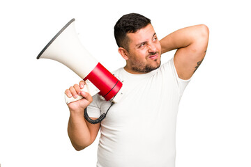 Young caucasian man holding a megaphone isolated touching back of head, thinking and making a choice.