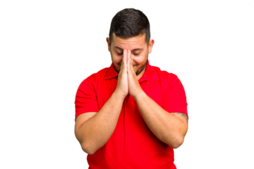 Young caucasian man isolated holding hands in pray near mouth, feels confident.