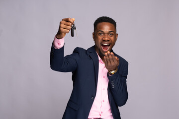 african man holding a car key looking surprised