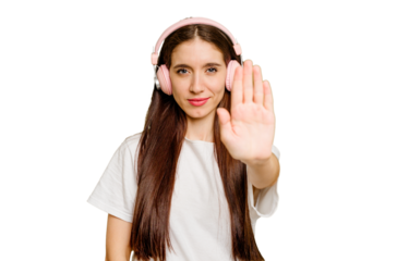 Young caucasian woman wearing headphones isolated standing with outstretched hand showing stop sign, preventing you.