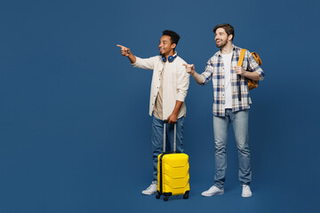 Traveler two friend men wear shirt hold bag backpack point finger aside isolated on plain dark royal navy blue background Tourist travel abroad in free spare time rest getaway Air flight trip concept