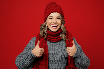 Young smiling happy cheerful woman wear warm gray sweater scarf hat show thumb up like gesture...