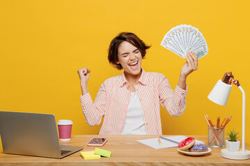 Young employee business woman wear shirt sit work at office desk with pc laptop hold fan of cash...