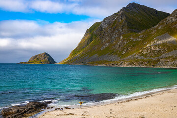 Fototapeta na wymiar aerial photography of long-haired girl walking on famous haukland beach in norway on lofoten islands; paradise beach in norwegian fjord with mighty mountains