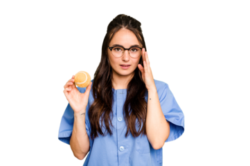 Young caucasian physiotherapist woman holding a tennis ball isolated isolated on green chroma background pointing temple with finger, thinking, focused on a task.