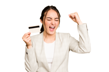 Young caucasian woman holding a credit card isolated on green chroma background raising fist after a victory, winner concept.